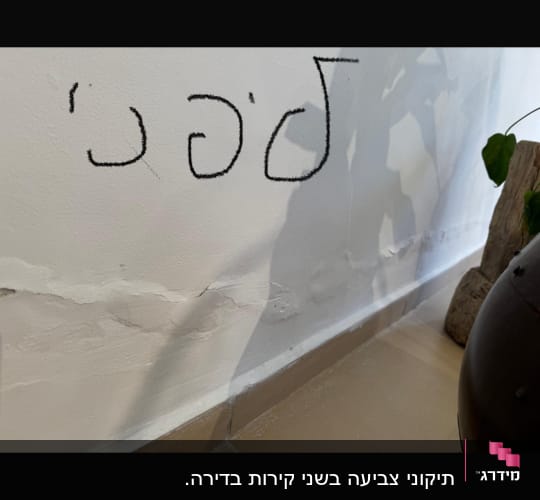 קיר עם סדקים וכתובת בעברית